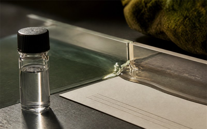 Clear fragrance liquid divides into two clean glass channels during a controlled formulation test, with no branding or text